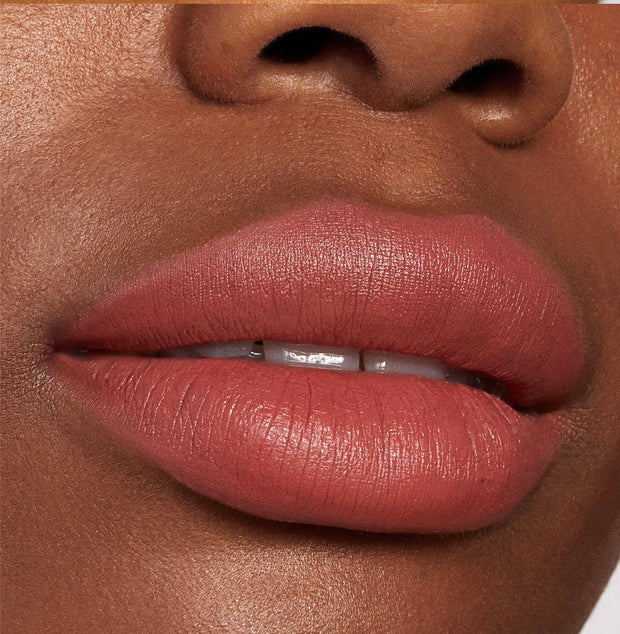 Lips wearing ColourPop Lippie Stix Brink, a warm rosy terracotta nude in a soft‑matte finish, shown in a close-up to highlight smooth, even coverage and creamy texture.