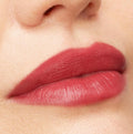 Lips wearing ColourPop Bumble Ultra Matte Lip, a warm rosy terracotta shade, showing full-coverage, velvety matte finish with crisp edges in a studio close-up on smooth skin.