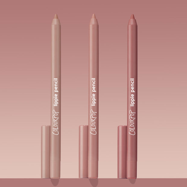 Trio of ColourPop Lippie Pencil Cool Besties standing upright, tips exposed, in light nude, pink nude, and rosy mauve tones with matching caps, arranged on a blush gradient background for a clean product shot.