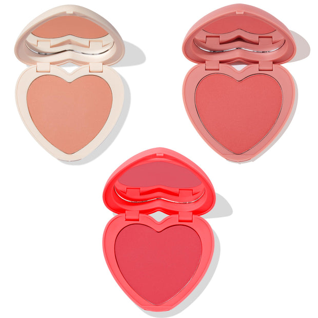 Current Crush heart powder blush set displaying three open heart-shaped compacts with mirrors - peach nude in ivory case, warm rose in pink, and bright coral-red in red - ColourPop Heart Powder Blush Set on a clean white background.