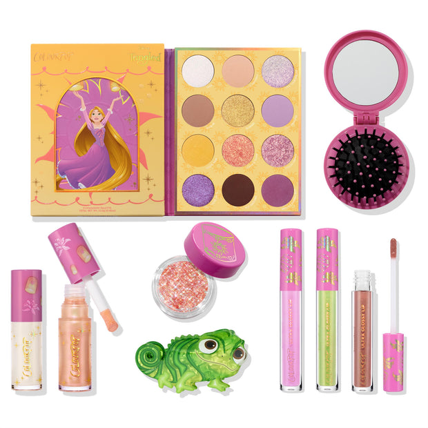 Disney Tangled and ColourPop Collection full collection set laid out on white, featuring Rapunzel-themed eyeshadow palette, glitter pot, pink compact brush, lip glosses, and Pascal figurine, promoting Back In Stock ColourPop makeup.