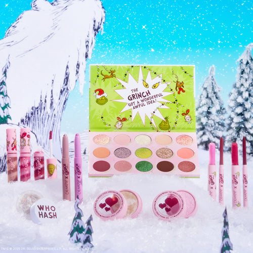 ColourPop x The Grinch Full Collection Set arranged on a snowy Whoville backdrop - open lime-green palette with 15 matte and shimmer shades and the quote “The Grinch got a wonderful awful idea!”, surrounded by pink lip crayons, glosses, highlighters, and glitter; holiday Colourpop makeup.