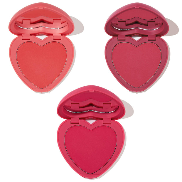 Three heart-shaped powder blush compacts open to show coral, berry, and hot pink pans with built-in mirrors on a white background, Heart to Heart ColourPop Heart Powder Blush Set for buildable, long-wear cheek color.