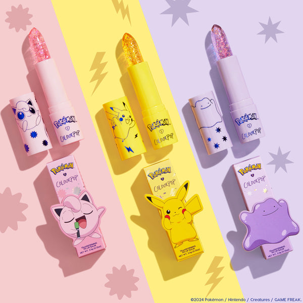 Sing pH Lip Balm by ColourPop x Pokémon, uncapped to show a pink glitter bullet with Jigglypuff art on a pastel pink tube, set in a flatlay alongside Pikachu and Ditto versions on a split pastel backdrop. ColourPop pH Lip Balm.