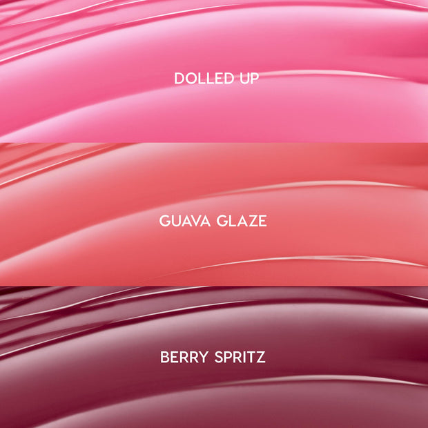 ColourPop So Juicy Plumping Gloss Balm with Peptides swatches showing She’s So Juicy shades: Dolled Up (bright pink), Guava Glaze (coral peach), and Berry Spritz (deep berry), displayed as glossy curved stripes in a close-up bundle layout.