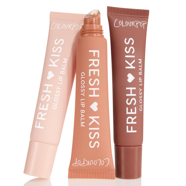 Sweet Treats ColourPop Glossy Lip Balm Trio standing in a fan: three Fresh Kiss squeeze tubes in blush pink, peach, and cocoa, center tube uncapped showing slanted applicator, set against a clean white background.