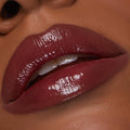 Glossy deep-berry lips wearing Juicy Berry, the ColourPop So Juicy Plumping Lip Liner & Balm Set defining the lip line while the balm delivers high-shine, plumped finish; close-up of a slightly parted mouth with teeth visible.
