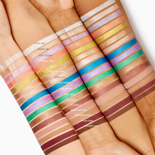 Cold Girl ColourPop Shadow Stix swatch - an icy white shimmer - painted as the top stripe across four arms in varying skin tones, lined with rows of other Shadow Stix shades for comparison, showcasing its bright, metallic payoff.