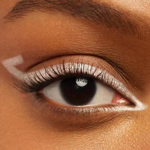 Eye wearing ColourPop Crème Gel Liner Calabasas, a pearly white shade, sweeping along the upper lash line with sharp inner and outer corner points; close-up highlights creamy, precise payoff and defined lashes on warm brown skin.