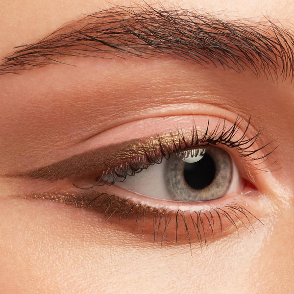 Metallic bronze-gold wing defines the upper and lower lash lines, showcasing Hit The Jackpot Crème Gel Liner, a ColourPop Crème Gel Liner, on a close-up eye with neutral shadow and natural lashes.