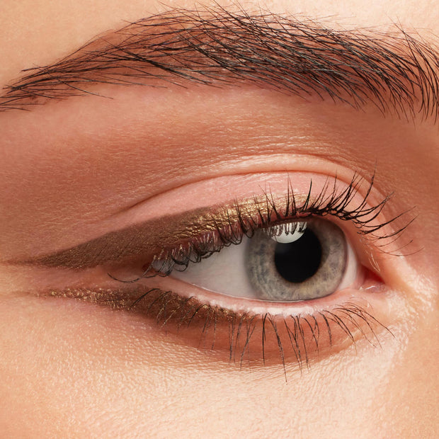 Metallic bronze-gold wing defines the upper and lower lash lines, showcasing Hit The Jackpot Crème Gel Liner, a ColourPop Crème Gel Liner, on a close-up eye with neutral shadow and natural lashes.