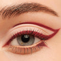 Burgundy graphic winged liner framing a gray-blue eye, created with Joy Ride, ColourPop Crème Gel Liner, tracing the upper crease and lower lash line with a sharp extended flick for a bold, precise look.