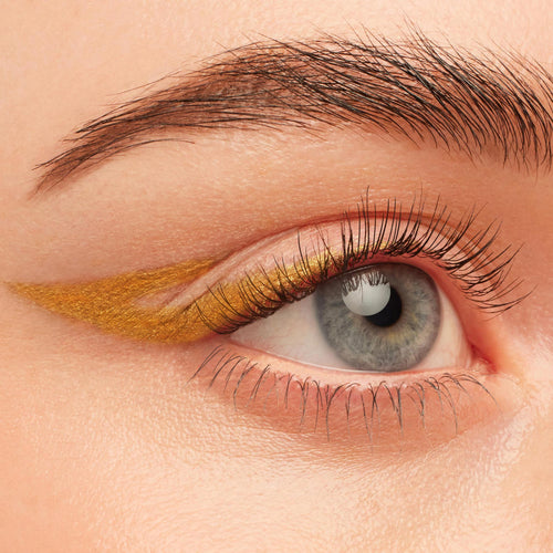 Wildcat Crème Gel Liner draws a sharp metallic gold cat-eye wing on the upper lash line of a blue eye in a close-up beauty swatch, showing smooth, precise payoff; ColourPop Crème Gel Liner in the Wildcat shade.