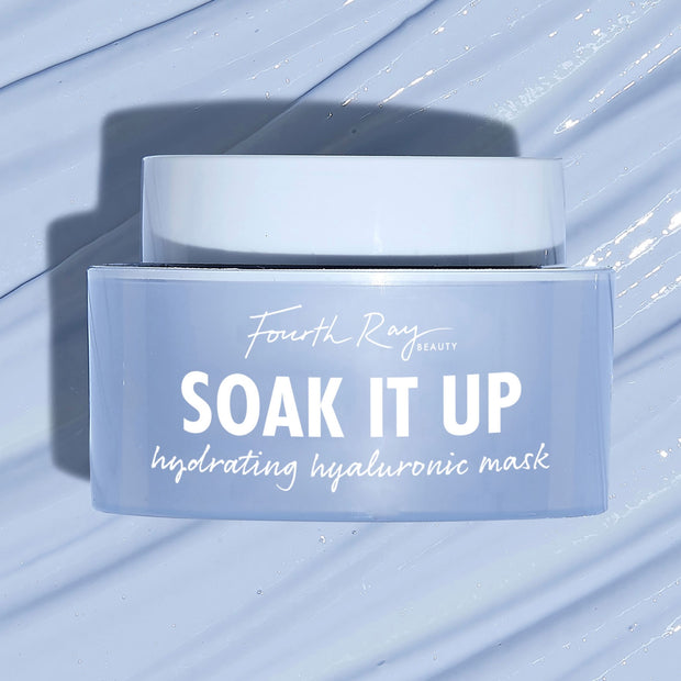 Fourth Ray Beauty Soak It Up Hydrating Mask jar shows “hydrating hyaluronic mask” as it rests on a glossy, water-swept pale blue surface; frosted periwinkle square container with white lid, a ColourPop Face Mask for dewy hydration.