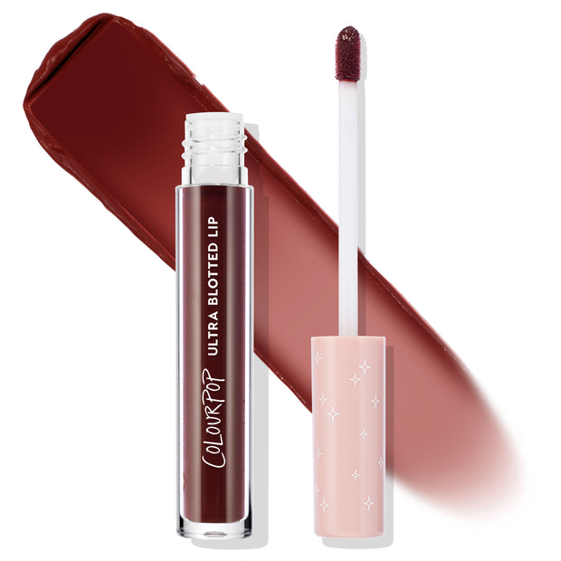 ColourPop Ultra Blotted Lip in Canon Dr shown uncapped with doe-foot applicator and a wide soft-matte swatch in deep brick red on white; clear tube reads Ultra Blotted Lip with a blush-pink starry cap, showcasing a lightweight blurred finish.