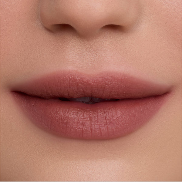 Close-up of smooth, full lips wearing Cloudy Hour Cloud Whip Blurring Liquid Lipstick in a soft mauve nude shade, showing a velvety, blurred-matte finish against natural, even-toned skin for a comfortable everyday lip look.