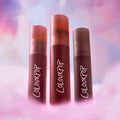 ColourPop Cloud Crushin lip trio standing upright in a dreamy pink and purple cloud backdrop, showcasing three blurring liquid lipsticks as a makeup Value Sets option for soft-focus, cloud-like lip color.