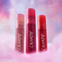 Three ColourPop Petal Plush lip trio tubes stand upright in fluffy pink clouds against a dreamy pastel sky, showcasing rich rosy and red shades as a colorful makeup value set for soft blurred lips.