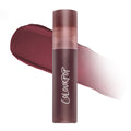 ColourPop Storm Cloud Cloud Whip Blurring Liquid Lipstick standing upright in a frosted mauve tube, shown against a blurred swatch of deep plum color on a white background, highlighting its soft-focus Cloud Whip finish.