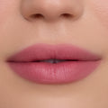 Close-up of smooth, full lips wearing What the Fluff Cloud Whip Blurring Liquid Lipstick in a soft matte pink shade, showing even, blurred edges and velvety texture against flawless natural skin.