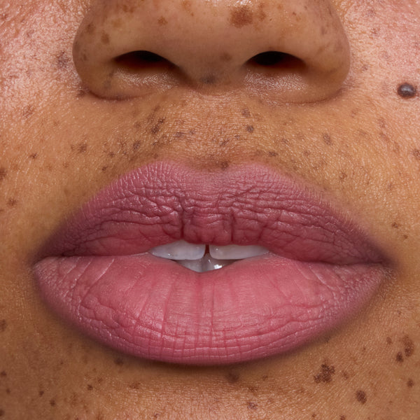 Close-up of freckled lips wearing What the Fluff Cloud Whip Blurring Liquid Lipstick in a soft matte pink shade, showing smooth, blurred edges and velvety Cloud Whip finish for an airy, lightweight lip look.
