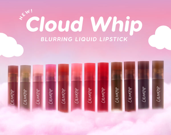 Row of ColourPop Cloud Whip blurring liquid lipstick tubes in assorted pink, red, and nude shades standing on fluffy pink clouds against a pastel sky, highlighting the new lightweight, soft-focus lip formula for US makeup lovers.