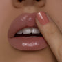 Glossy lips apply Coconut ColourPop Lip Mask with a fingertip, revealing a smooth, hydrating shine in a studio close-up with a pink-manicured nail, highlighting the lip mask’s moisture-rich finish.