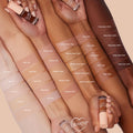 ColourPop Pretty Fresh Creamy Concealer in Fair 05 W swatched on an arm and compared across multiple skin tones, with a peach-capped tube held in hand against a soft beige background to showcase the full shade range.