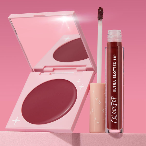 Blush n' Pout ColourPop Cheek & Lip Set showcasing an open pink compact with mirror and rosy-mauve cream blush with star accents, beside a ColourPop Ultra Blotted Lip tube and doe-foot applicator tipped in berry, on a pink studio backdrop.