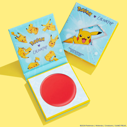 ElectroBall cream blush compact opens to a vibrant red round pan, highlighting a ColourPop Cream Blush in the Pokémon x ColourPop collection, with Pikachu graphics on an aqua-and-yellow box, styled on a bright yellow backdrop.