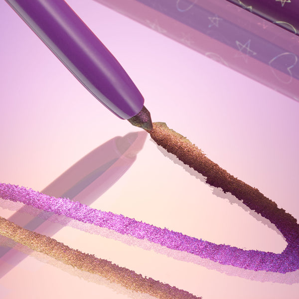 ColourPop Chrome Crème Gel Liner in Actin' Up draws a bold, shimmering purple-to-bronze stroke on a reflective pink surface, with the purple barrel and star-patterned cap nearby, showcasing metallic duochrome payoff for precise eye looks.