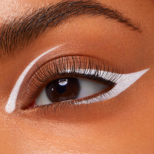 White winged liner defines the upper lash line with a crisp cat-eye and inner-corner accent on a close-up eye, showcasing Exit, the ColourPop Crème Gel Liner, delivering a sharp, graphic finish.