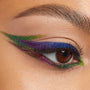 Chrome Hearted Chrome Crème Gel Liner swept into a bold graphic double wing, shifting green-gold to violet-blue across a brown eye with crisp inner-corner and lower-lash accents; ColourPop Chrome Crème Gel Liner delivers multichrome sparkle.