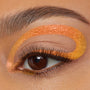 Chrome Hearted ColourPop Chrome Crème Gel Liner sweeps in a bold metallic orange-to-gold loop over and under a brown eye, accenting long lashes in a crisp studio close-up beauty shot.