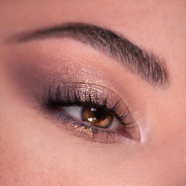 Glittering bronze and mauve eyeshadow blends on a brown eye with fluttery lashes and a groomed brow, created using the 11:11 Shadow Palette, a ColourPop Shadow Palette delivering day-to-night metallic sparkle.