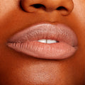 Close-up lips wearing BFF, lined and softly filled with ColourPop Lippie Pencil, showing a creamy matte peachy‑nude shade with precise edges and smooth texture against warm brown skin in a studio setting.