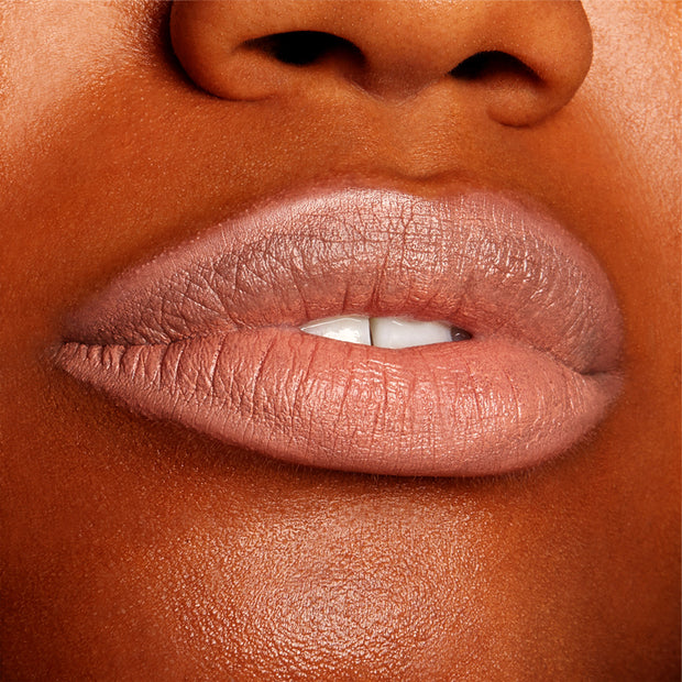 Close-up lips wearing BFF, lined and softly filled with ColourPop Lippie Pencil, showing a creamy matte peachy‑nude shade with precise edges and smooth texture against warm brown skin in a studio setting.