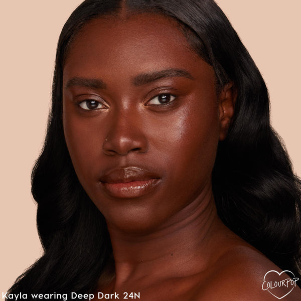 Face wearing ColourPop Pretty Fresh Tinted Moisturizer in Deep Dark 24 N, showcasing a smooth, dewy, even tone with neutral undertones; close-up studio portrait on a soft beige background highlighting shade match and glow.