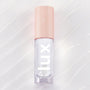 ColourPop Dew Drop Lux Lip Oil lying flat, a clear high-shine formula in a rectangular tube with blush-pink cap printed with starbursts and bold lux lettering, set on a pearlescent swirled backdrop for a glossy finish.