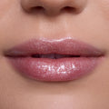 Close-up of lips wearing Bright Ariel Ultra Glossy Lip, a shimmering pink Disney Princess lip gloss with high-shine, reflective sparkle on smooth, fair skin, showcasing moisturizing, ultra-glossy finish for everyday glam makeup looks.