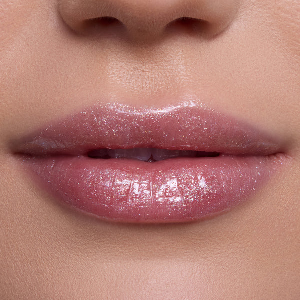 Close-up of lips wearing Bright Ariel Ultra Glossy Lip, a shimmering pink Disney Princess lip gloss with high-shine, reflective sparkle on smooth, fair skin, showcasing moisturizing, ultra-glossy finish for everyday glam makeup looks.