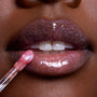 Close-up glossy lips wearing Courageous Rapunzel Ultra Glossy Lip, a shimmery purple-pink Disney Princess lip gloss, as a wand applicator glides on sparkling color for a high-shine finish.