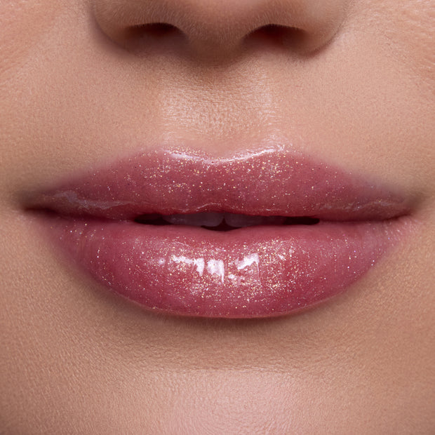 Close-up lips wearing Mademoiselle Belle Ultra Glossy Lip, a shimmery pink Disney Princess lip gloss with high-shine, sparkly finish on smooth, light-toned skin, showing moisturizing, ultra-gloss texture for a glam beauty look.
