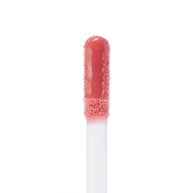 Doe-foot applicator coated in Ditto Ultra Glossy Lip, a peachy-pink high-shine ColourPop Ultra Glossy Lip, captured in a macro close-up on a white background highlighting the smooth glossy texture.