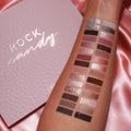 Rock Candy ColourPop Shadow Palette swatched on a forearm, showcasing neutral mattes and sparkling metallics from champagne and rose to bronze and charcoal beside the pink textured palette on a satin backdrop.