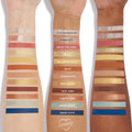 ColourPop Beauty and the Beast shadow palette swatched on three forearms, labels showing shades from Vivid Imagination, Forbidden, Break the Curse and Belle to Book Lover and Dinner Invite in matte, shimmer and glitter across champagne, gold, warm brown and deep blue tones.