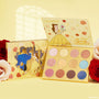 ColourPop Shadow Palette Beauty and the Beast opens to show 12 pans in pinks, golds, corals, and blues with matte and glitter finishes, Belle art on a yellow case, with matching box and roses on a soft yellow background.