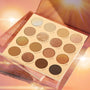Golden Hour ColourPop Shadow Palette opened to 16 warm-tone pans - mattes and metallic gold, bronze, and copper shimmers like Glimmer, Golden Waves, and LA Sunset - sparkling under sun flares on a glossy peach background with stacked packaging.