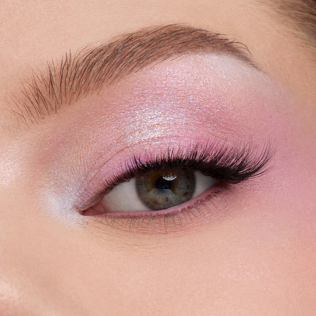 Shimmering pastel pink‑lilac eyeshadow blends across a close-up eyelid with fluttery lashes, showcasing the color payoff of the In A Trance shadow palette, a ColourPop Shadow Palette, perfect for soft, iridescent looks.
