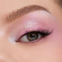 Shimmering pastel pink‑lilac eyeshadow blends across a close-up eyelid with fluttery lashes, showcasing the color payoff of the In A Trance shadow palette, a ColourPop Shadow Palette, perfect for soft, iridescent looks.